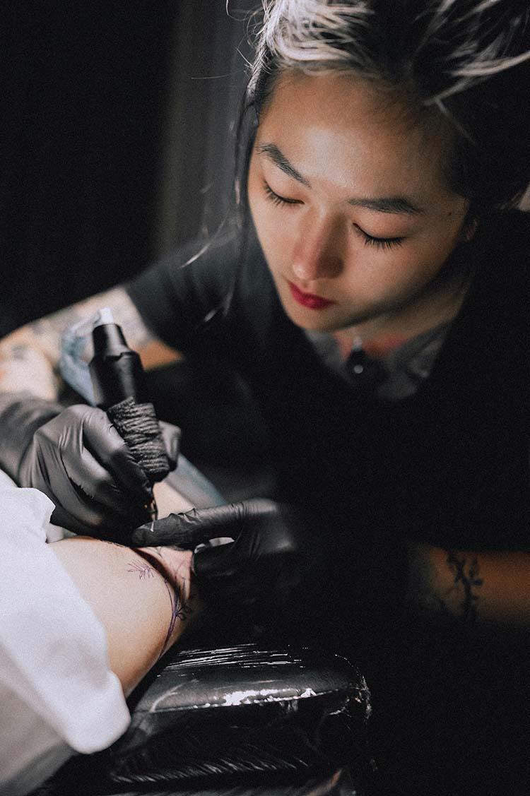 Woman tattooing a client in a studio
