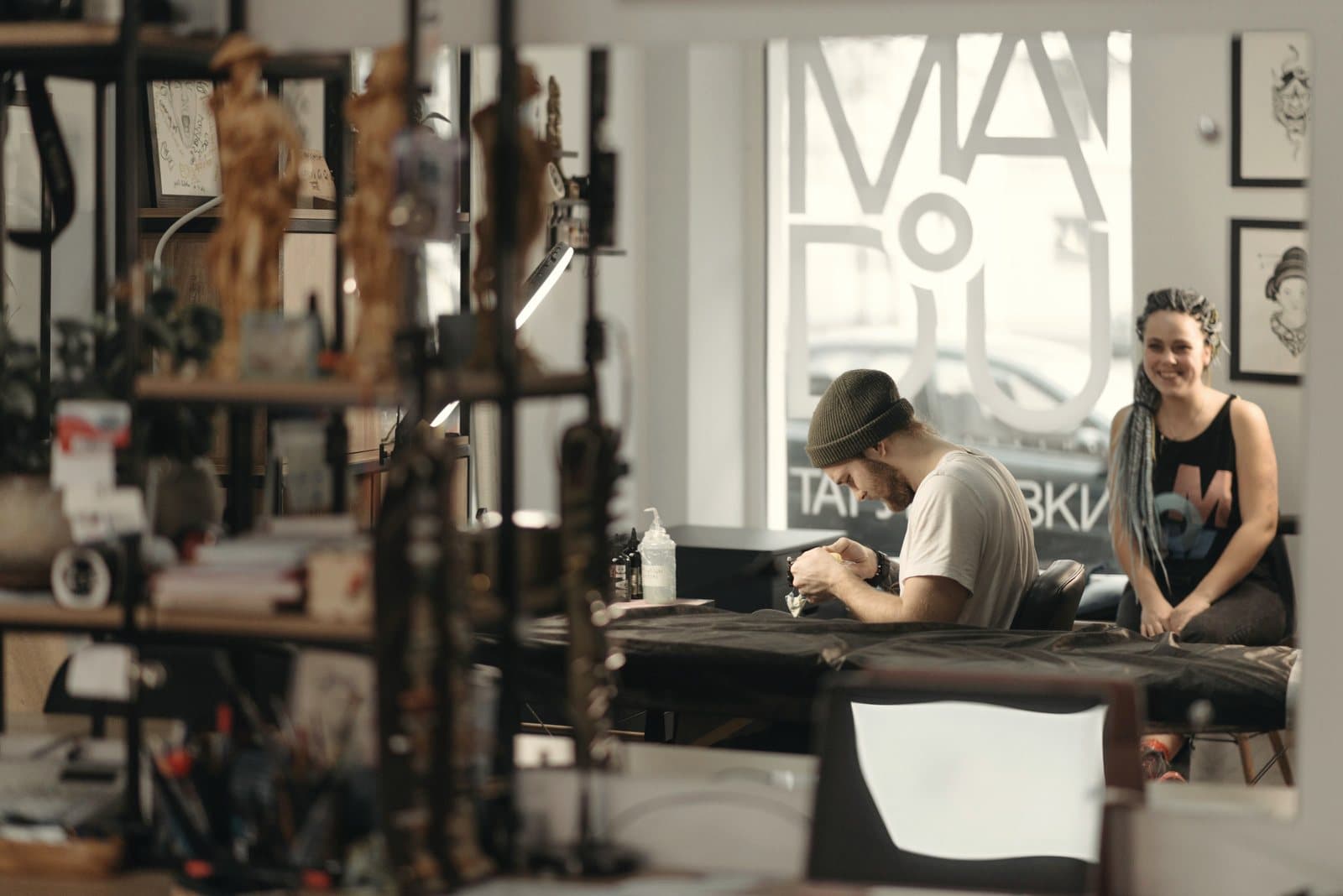 Tattoo artist working in a busy studio while a client looks on