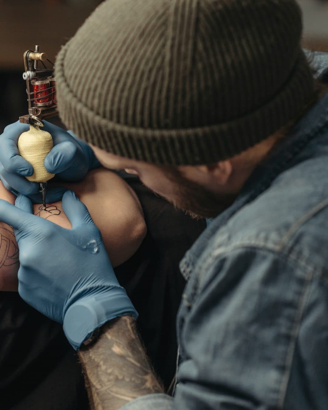 Um tatuador trabalha no ombro de uma cliente durante uma sessão marcada