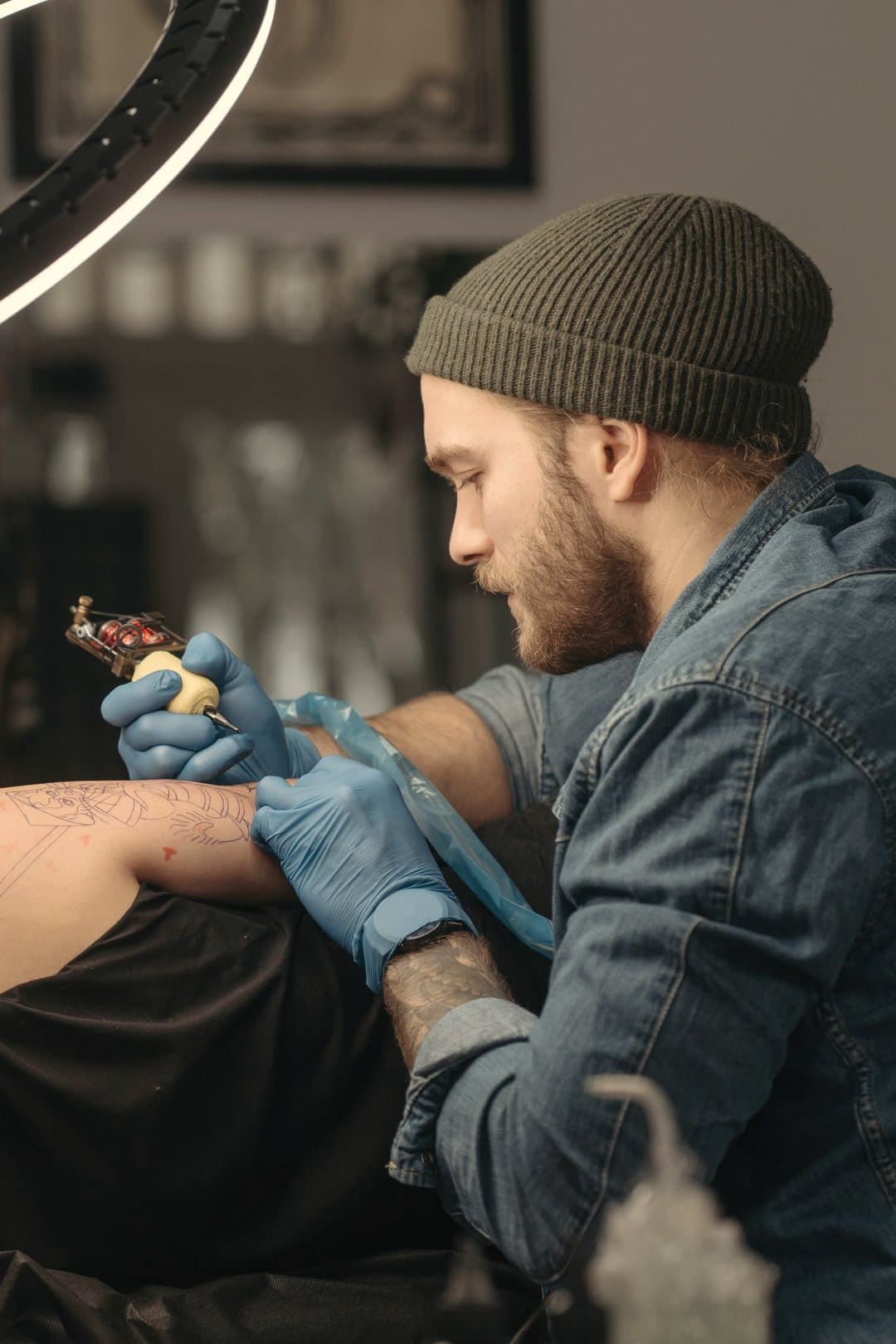 Tattoo artist tattooing a client's leg