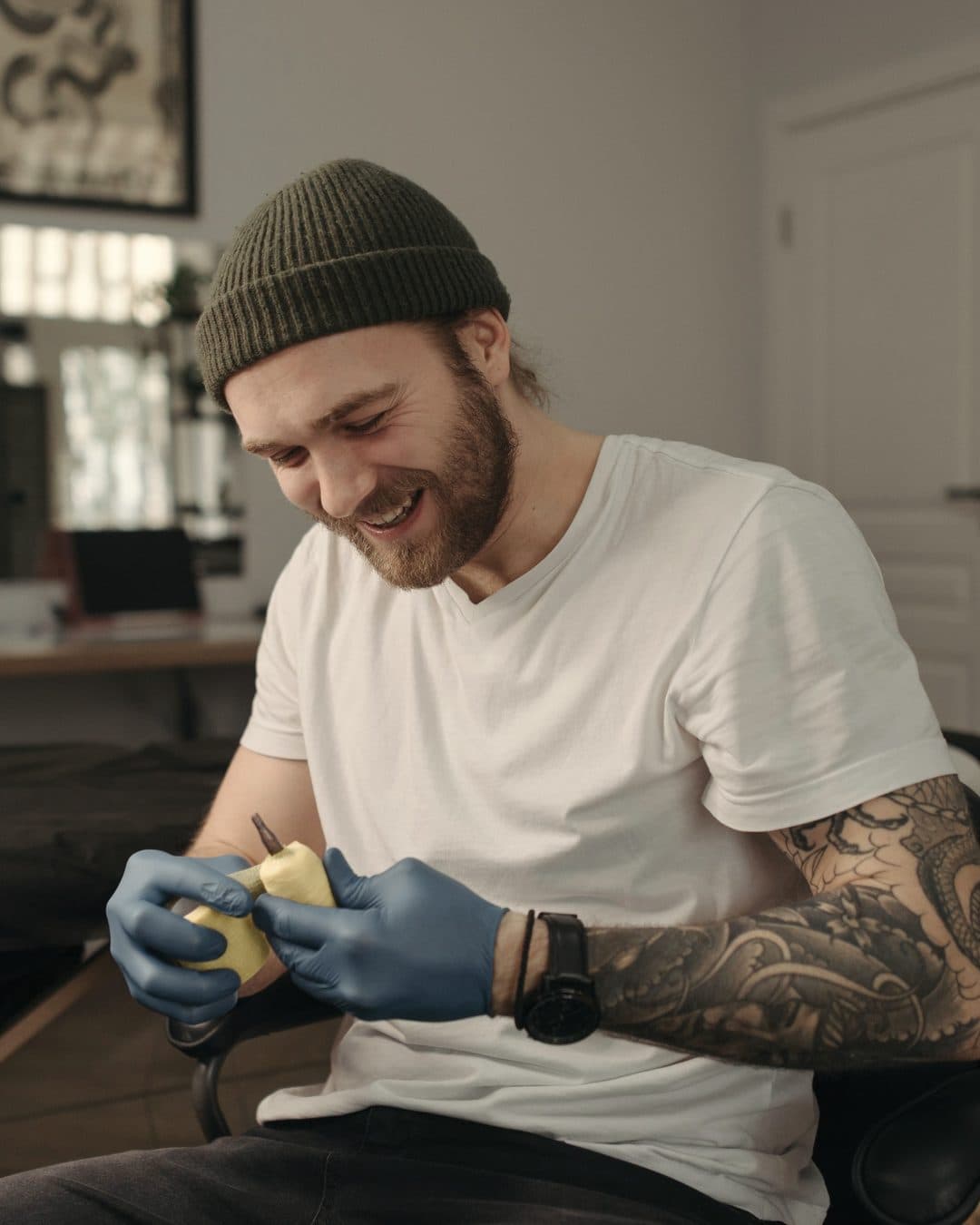 Un tatuatore sorride mentre prepara la macchinetta in studio
